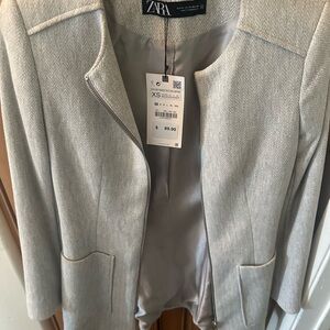 Blazer with pockets and zipper front. Tailored to fit light grey